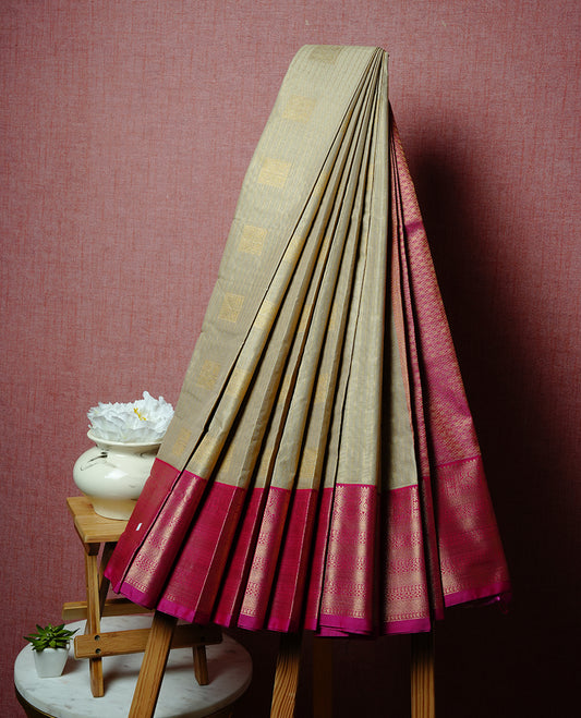 Cream coloured soft silk saree featuring gold zari stripes and motifs across the body, enhanced with a contrast Magenta border and pallu, paired with a matching contrast blouse piece.