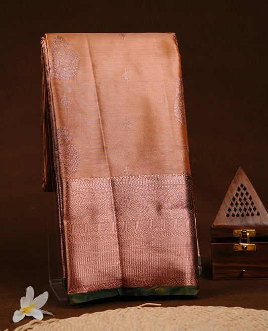 Rose gold colour semi tissue silk saree featuring gold zari motifs on body, self colour with copper zari traditional green simple border, paired with matching blouse piece.