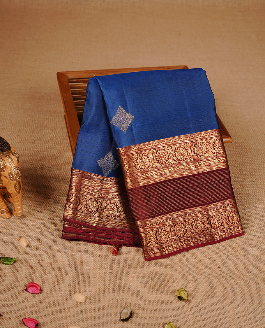Navy blue colour traditional kancheepuram silk saree featuring gold zari strpies on body, complemented by contrast maroon colour with gold zari traditional border, paired with matching blouse piece.