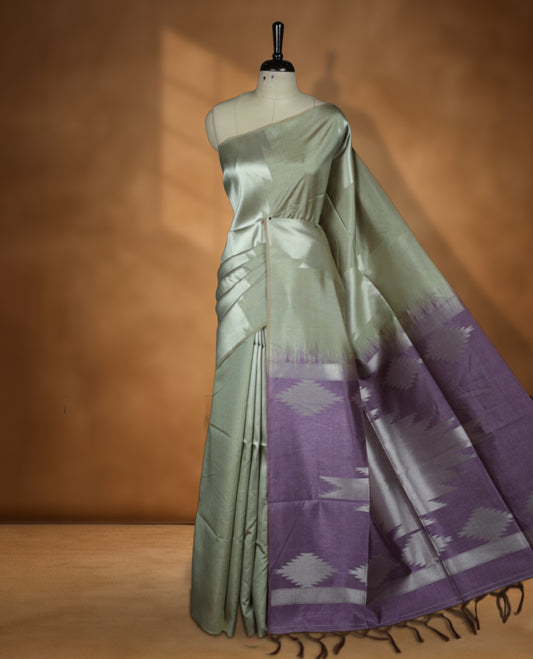 Olive and silver colour dual tone semi tussar saree featuring woven abstract geometric motifs on the body, complemented by a ikat inspired contrast Lavender purple patterned pallu, paired with a matching blouse.