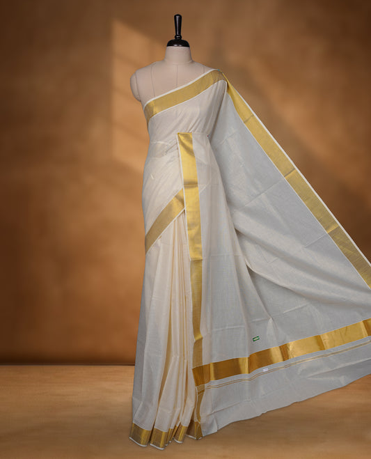 Off-white colour cotton Kerala saree featuring a traditional gold kasavu border with a fine striped texture across the body and pallu, offering a clean, elegant look, and paired with a matching blouse.