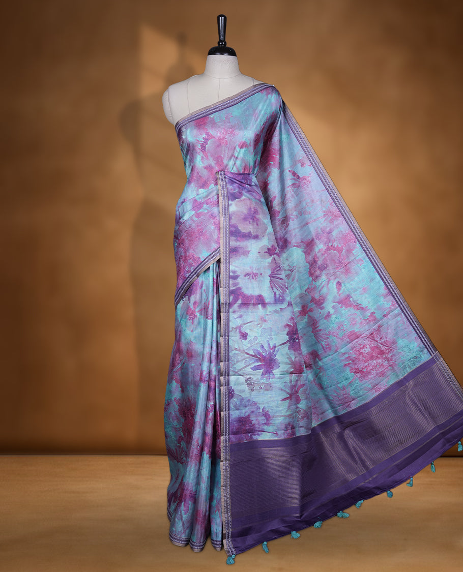 Aqua green colour semi tussar silk saree featuring an abstract digital floral printed body with a rich purple self border and tasselled pallu, paired with a matching blouse.