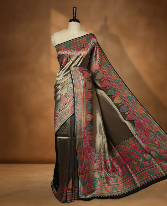 Antique bronze colour Pashmina silk saree featuring a sleek plain body, highlighted with an opulent multicolour paisley and floral panelled border and grand pallu, paired with a contrasting black woven jaal blouse piece.
