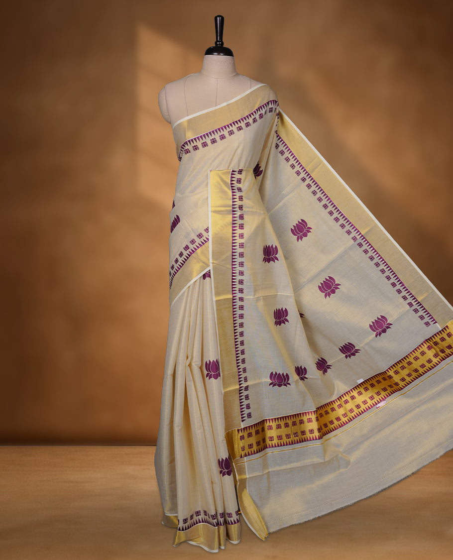 Off-white colour Tissue Kerala saree featuring elegant purple lotus motifs across the body, highlighted with a classic gold kasavu border and matching woven pallu, paired with a coordinating blouse.