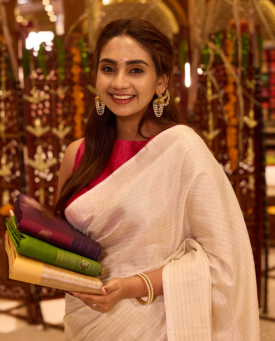 Elegant Ivory colour Kancheepuram silk saree enriched with a subtle sheen, gracefully contrasted by a bold Rani Pink pallu that adds a festive touch, styled with a matching blouse