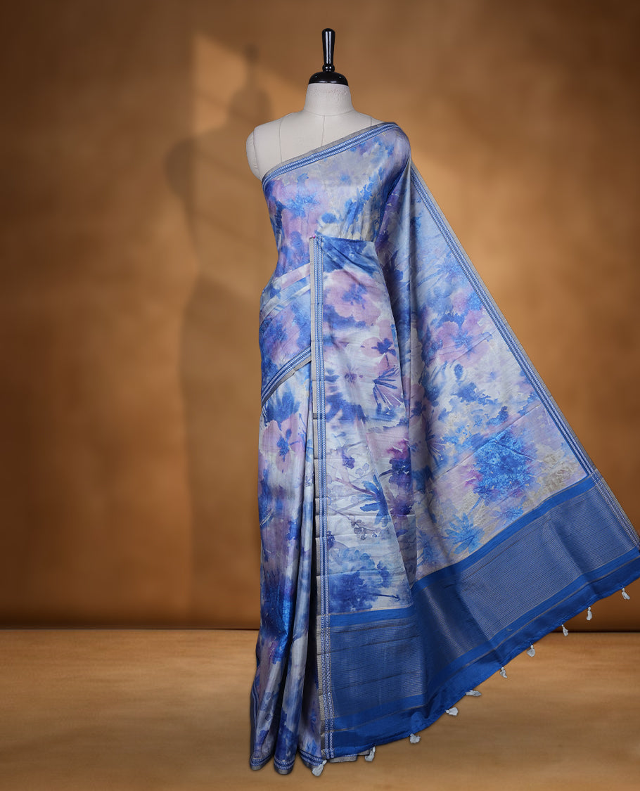 Royal blue colour semi tussar silk saree featuring an abstract digital floral printed body with a rich self border and tasselled pallu, paired with a matching blouse.