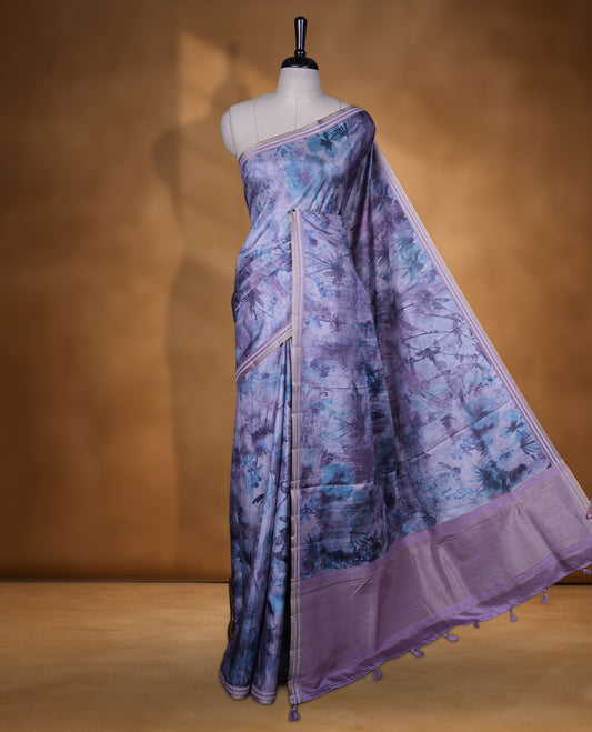 Lavender Purple colour semi tussar silk saree featuring an abstract digital floral printed body with a rich self border and tasselled pallu, paired with a matching blouse