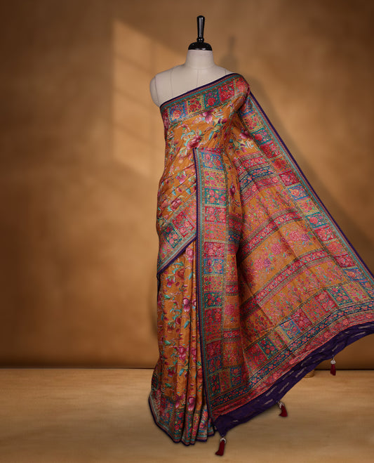 Mustard colour Pashmina silk saree richly woven with vibrant floral jaal across the body, framed by contrast pink and teal panelled zari borders and a grand patterned pallu, paired with a deep purple woven motif blouse piece.