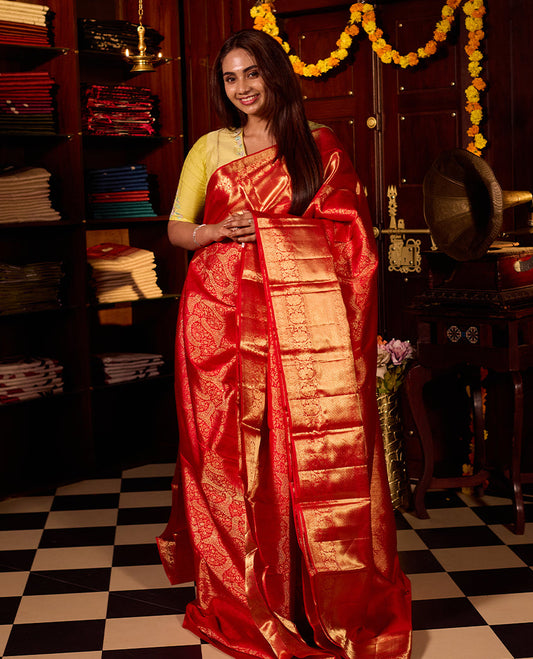 Rich red pure Kancheepuram silk saree featuring intricate gold zari weaving, a lustrous gold zari pallu, and a broad gold zari border, beautifully paired with matching blouse.