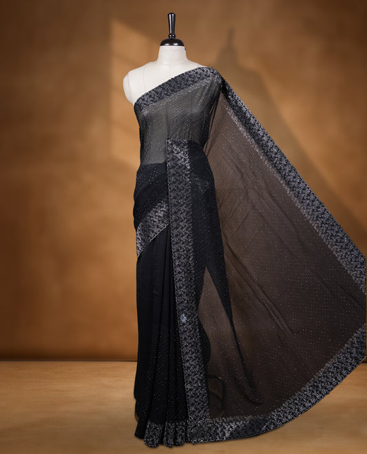 Black colour chiffon designer saree, featuring white stone all over on body, heavy stone patttern on border and  pallu, Paired with matching blouse.
