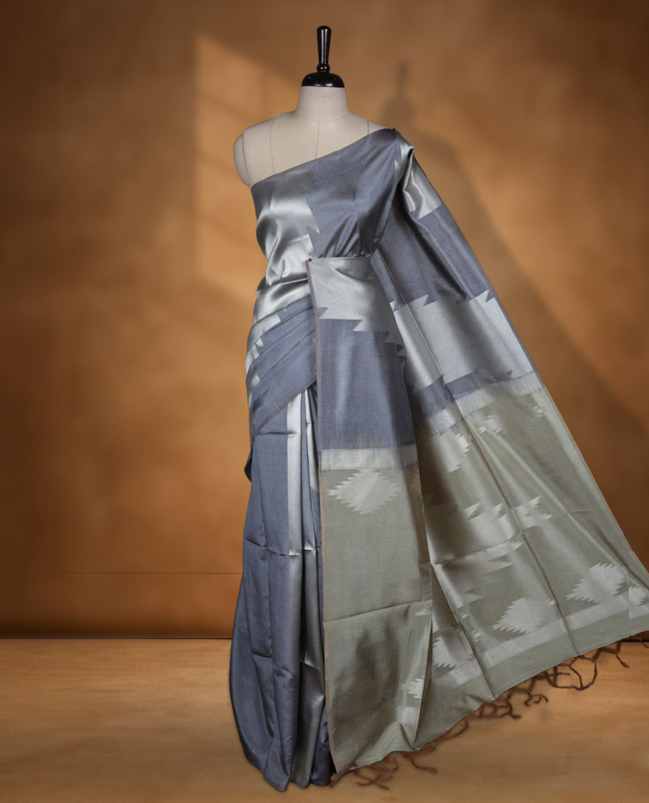 Gray and silver colour dual tone semi tussar saree featuring woven abstract geometric motifs on the body, complemented by a ikat inspired contrast olive patterned pallu, paired with a matching blouse.