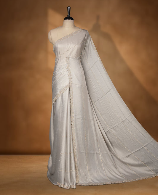 Gray silver Colour net shimmer fancy saree adorned with strip gold stone buttas all over the body, paired with a delicate stone worked border and matching blouse