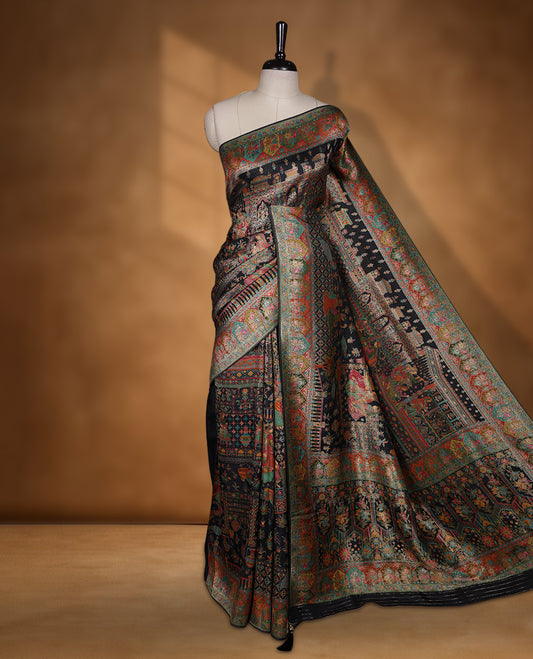 Black colour Pashmina silk saree densely woven with intricate multicolour floral and architectural motifs across the body, framed by an opulent arabesque border and grand storytelling pallu, paired with a matching black woven border blouse piece