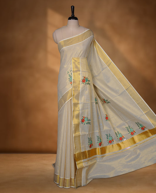 Off-white Kerala kasavu saree with delicate floral embroidery, finished with a classic gold border and paired with a matching blouse.