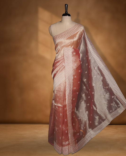 Pastel peach colour organza saree featuring white thread embroidery motifs on body and  thread detailing on the border and paired matching blouse.