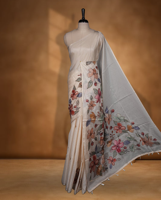 Ivory off white semi tusser silk saree featuring delicate multicolour floral prints across the pallu and lower body finished with a subtle self border and paired with a matching floral printed blouse.