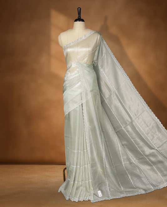 Ash Green Colour net shimmer fancy saree adorned with strip white stone buttas all over the body, paired with a delicate stone worked border and matching blouse