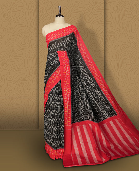 Black colour Ikkat Pochampally saree featuring bold geometric motifs in grey colour with a striking red colour contrast border with grey and orange colour zigzag & beautifully blending tradition with elegance.