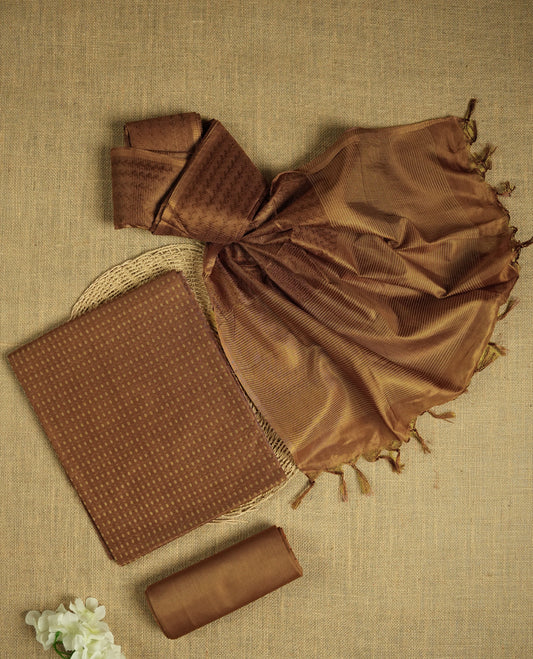 Pastel brown colour tussar suit material adorned with intricate woven patterns and subtle motifs, exuding ethnic elegance & Paired with a beautifully bordered dupatta and a matching plain bottom.