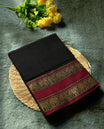 Black colour Narayanapattu cotton saree with a plain body and maroon borders featuring traditional golden elephant motifs & A timeless ethnic piece, this saree comes without a blouse piece.