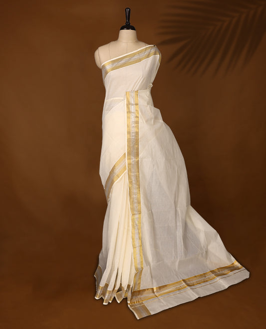 Traditional off white colour cotton Kerala saree featuring a subtle golden and silver dual tone zari border and pallu. Light, elegant, and perfect for festive or cultural occasions, it comes with a matching blouse piece.