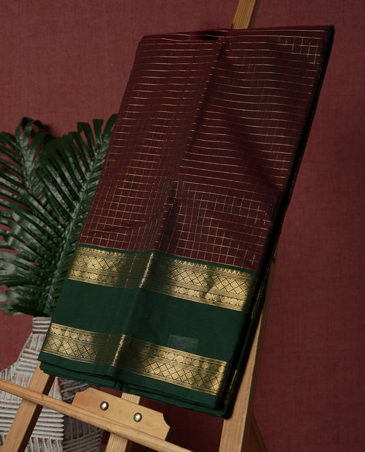 Dark Coffee Brown colour pure Kanchi cotton saree featuring with delicate golden checks on body, paired with a contrasting green zari woven border & Includes a matching blouse piece for a complete look.