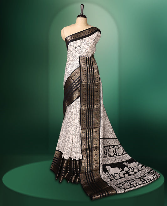 White colour saree adorned with striking black floral and cow prints across the body, enhanced by a rich black border for bold contrast, and paired with a matching blouse