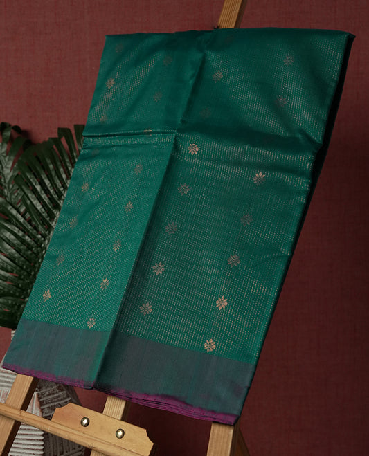 Teal colour pure handloom cotton saree featuring fine golden stripes with delicate motifs, paired with a rich zari purple double shaded border for a traditional yet elegant look, perfect for graceful occasions & Comes with matching blouse.