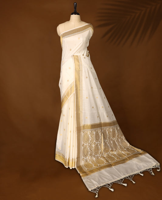 Elegant Kerala Kasavu saree with golden polka motifs and a detailed paisley woven pallu, Finished with tassels, its perfect for festive or traditional wear, Pair with a gold blouse for a classic look.
