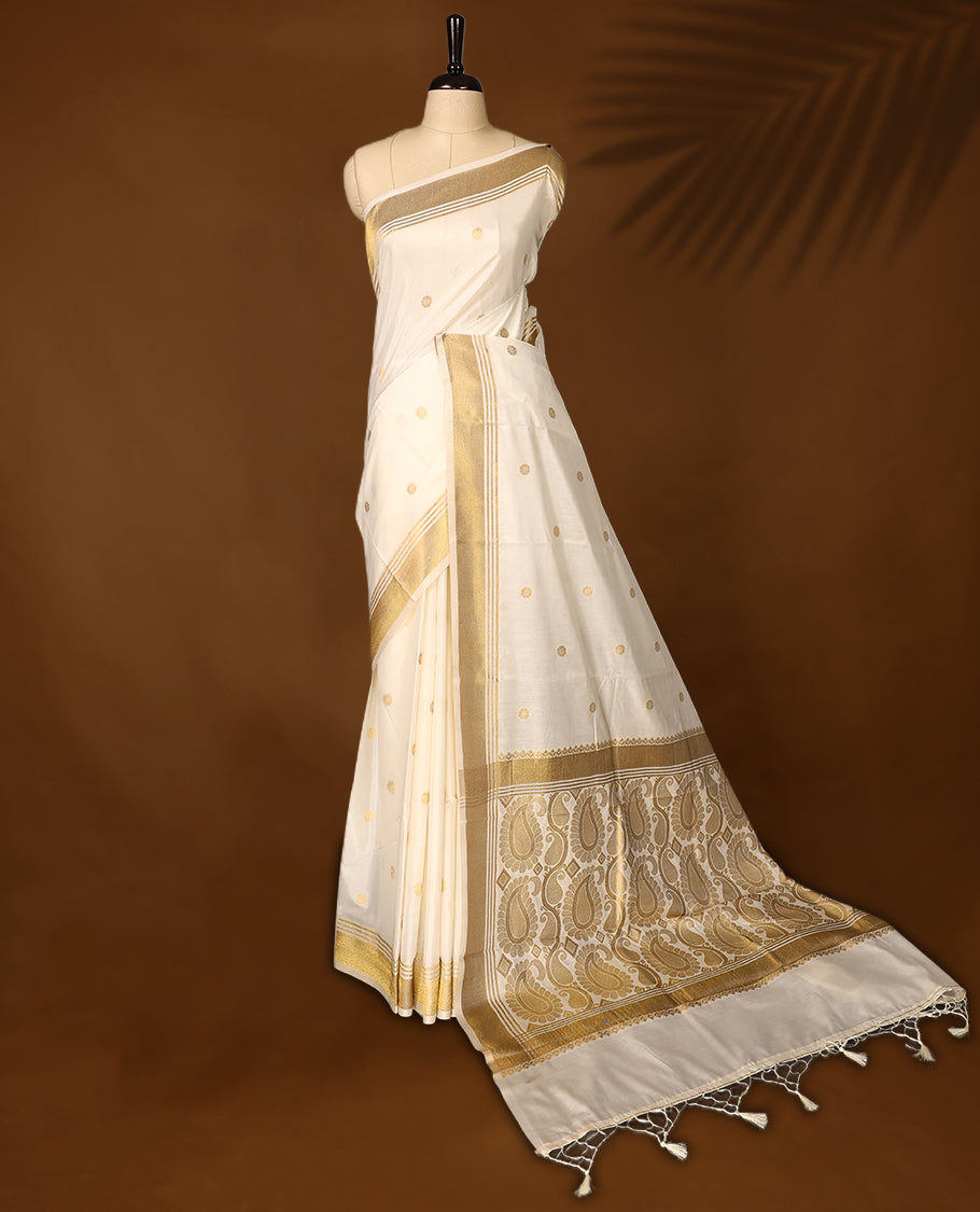 Elegant Kerala Kasavu saree with golden polka motifs and a detailed paisley woven pallu, Finished with tassels, its perfect for festive or traditional wear, Pair with a gold blouse for a classic look.