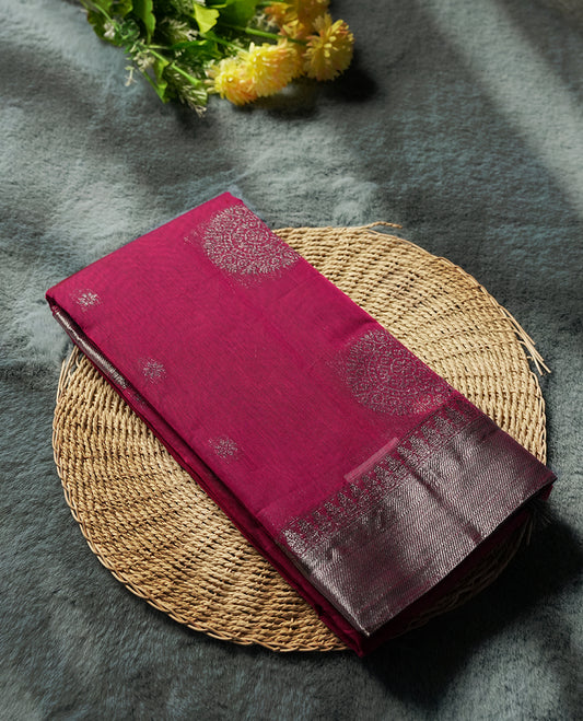 Magenta colour silk cotton saree adorned with a shimmering silver zari border and intricate woven designs, blending elegance with tradition, Paired with a matching blouse, its perfect for festive and special occasions.