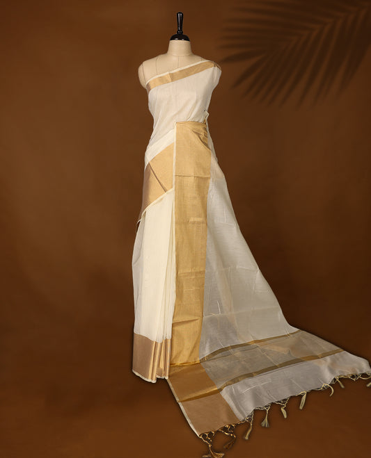 Elegant Off white colour Kerala saree with a traditional golden zari border and pallu, finished with golden tassels & A timeless ethnic piece, perfect for festivals and celebrations, paired with a matching blouse.