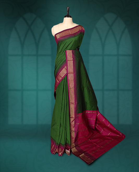 Deep green semi silk saree with plain body, vibrant deep magenta pallu and matching magenta border adorned with golden zari, accented with temple motifs along the edges, Paired with a matching blouse, perfect for festive occasions.