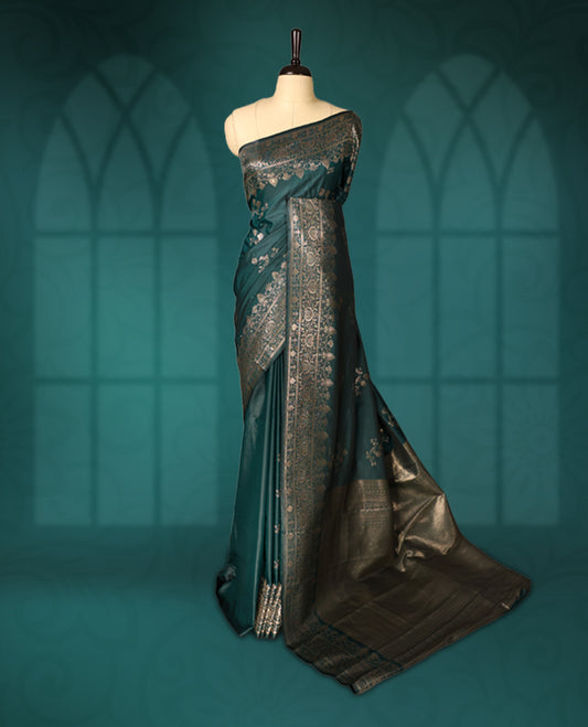 Teal green colour semi silk saree featuring elegant silver zari floral motifs across the body, complemented by a rich self-colour woven border and pallu, paired with a matching blouse.