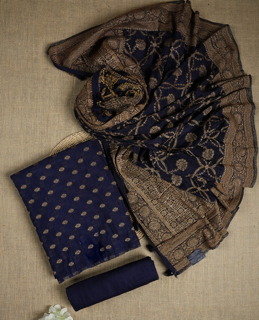 Navy blue colour suit material adorned with intricate golden zari weaving, exuding timeless elegance & Paired with a beautifully woven dupatta featuring floral and geometric motifs and a matching plain bottom.