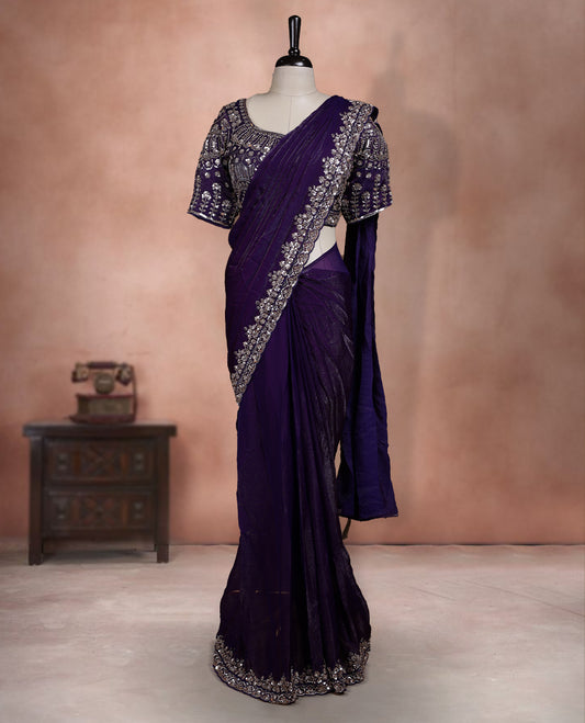 Elegant deep purple ready to wear saree adorned with rich silver zari and bead embroidery along the border and pallu, paired with a heavily embellished matching blouse for a grand festive look.