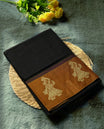 Black colour Narayanapattu cotton saree with a plain black body, mustard yellow pallu adorned with traditional dancer motifs in thread work, and a maroon striped border & A cultural classic, this saree comes without a blouse piece.
