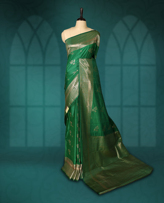 Green colour semi silk saree featuring golden zari floral motifs all over the body, complemented by a rich self colour woven border, with matching blouse.
