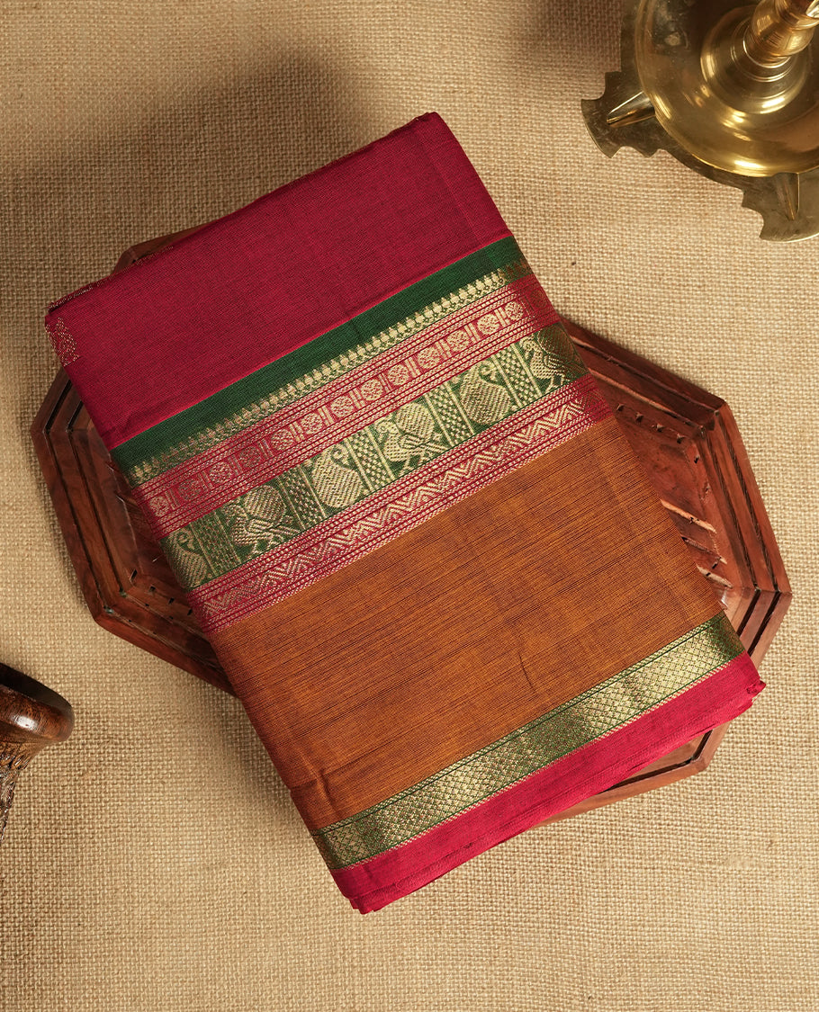 Dark marooon colour Chettinad cotton saree adorned with small peacock motifs on the body, it features a contrast maroon and brown border highlighted with intricate green and golden zari weaving & Comes with a matching blouse piece.