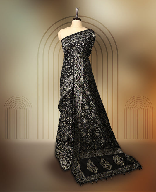 Classic black Banaras soft silk saree adorned with silver zari floral vines, detailed woven border, and grand paisley pallu, Comes with a matching blouse & A regal pick for festive and formal occasions.