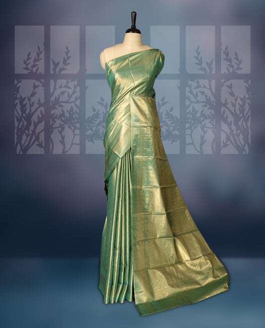 Green semi silk brocade saree featuring delicate self brocade motifs across the body, enhanced with a soft gold toned woven border and pallu, Includes a matching blouse for a graceful ethnic look.