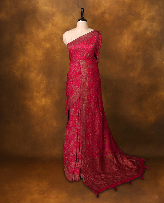 Reddish pink Banarasi Bandhani saree featuring Bandhani dots in checkered zari motifs, a beautifully woven zari border, and a grand pallu with tassels. A graceful pick for festive and wedding wear.
