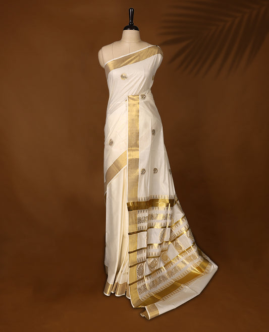 Graceful Kerala Kasavu saree with golden zari motifs and richly woven pallu, the ivory base and elegant border make it perfect for festive and traditional occasions, Pair with temple jewelry for a classic look.