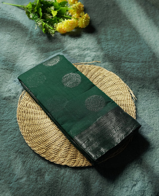 Dark green colour silk cotton saree with shimmering silver zari border and intricately woven pallu, blending elegance and tradition, Paired with a matching blouse, perfect for festive celebrations and special occasions.