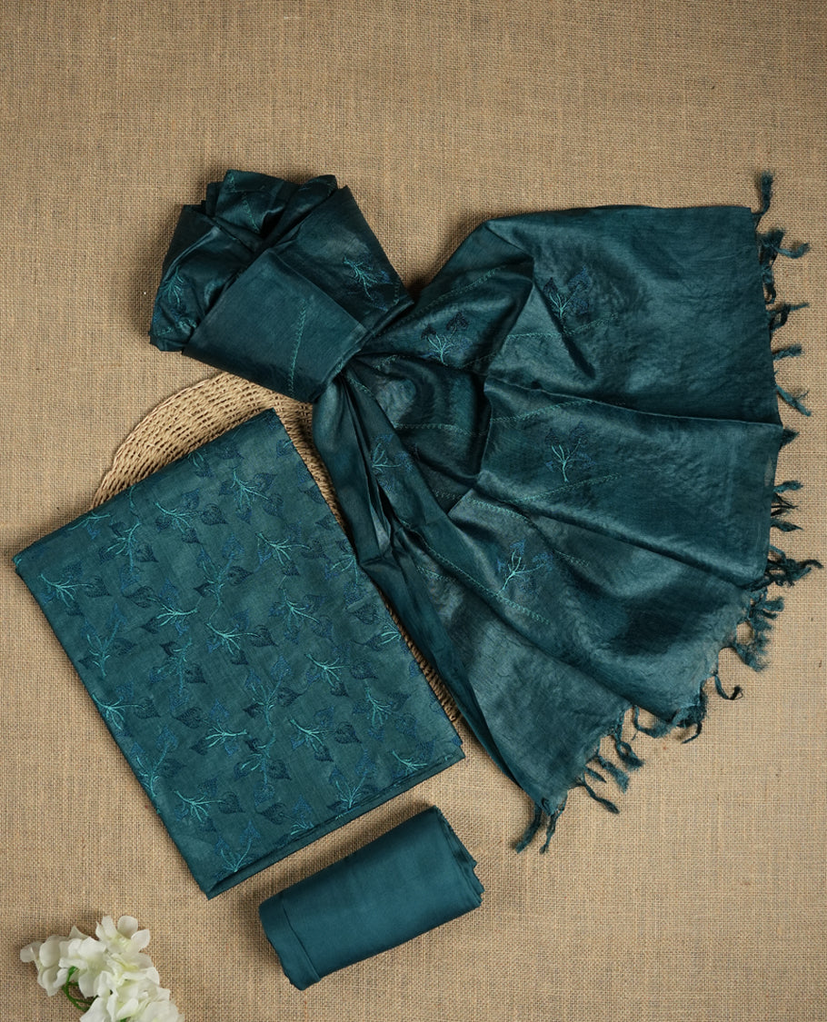 Crystal teal colour tussar suit material featuring elegant floral thread embroidery on the body, paired with a soft dupatta adorned with matching embroidered motifs and tassel edges, along with a plain bottom piece.