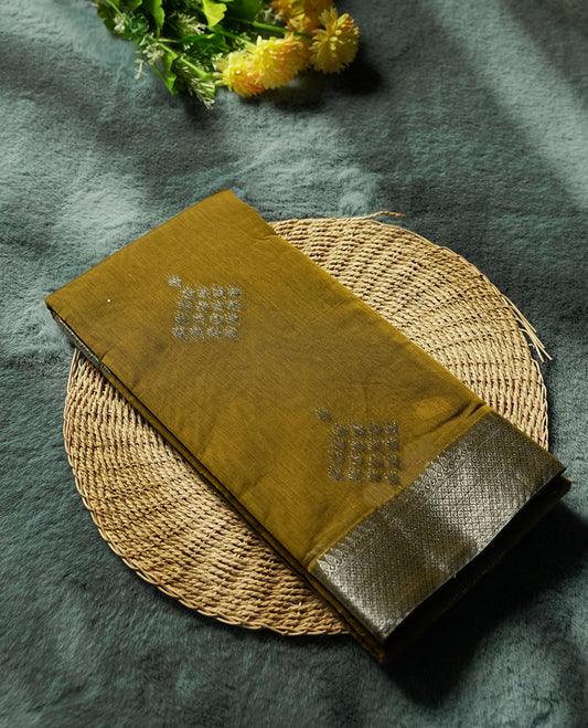 Bronze yellow colour silk cotton saree adorned with silver zari buttas and a rich zari border, complemented by a finely woven pallu & Paired with a matching blouse, perfect for festive gatherings and traditional occasions.