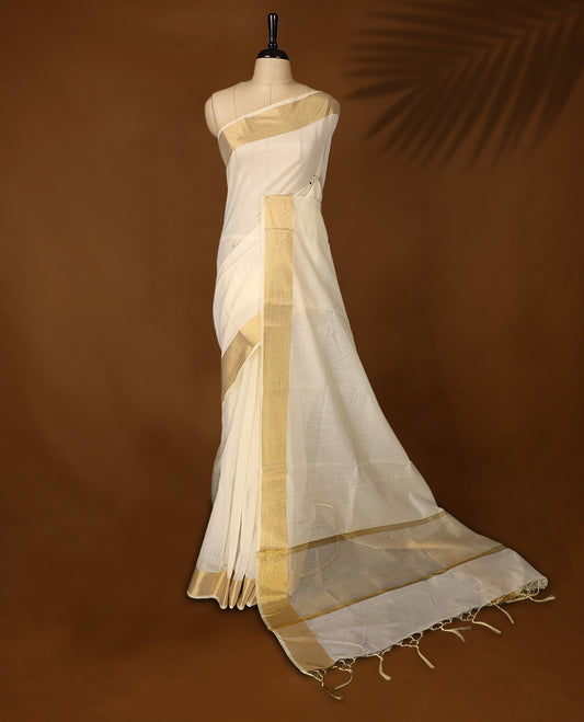 Classic off white colour Kerala saree adorned with a shimmering golden zari border and pallu, finished with elegant tassels. Perfect for festive or traditional occasions, and comes with a matching blouse piece.