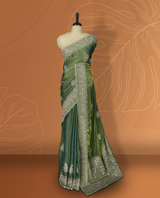 Asparagus green colour velvet chiffon designer saree in elegant two tone shades, featuring light gold zari, kodi work with handwoven style thread aari & dori embroidery work, Swarovski stone work and all over motifs, comes with matching blouse.