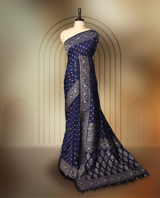Graceful navy blue Banaras soft silk saree with gold zari buttas on the body, intricate floral zari border, grand pallu with paisley motifs, and a matching blouse. Perfect for weddings and celebrations.