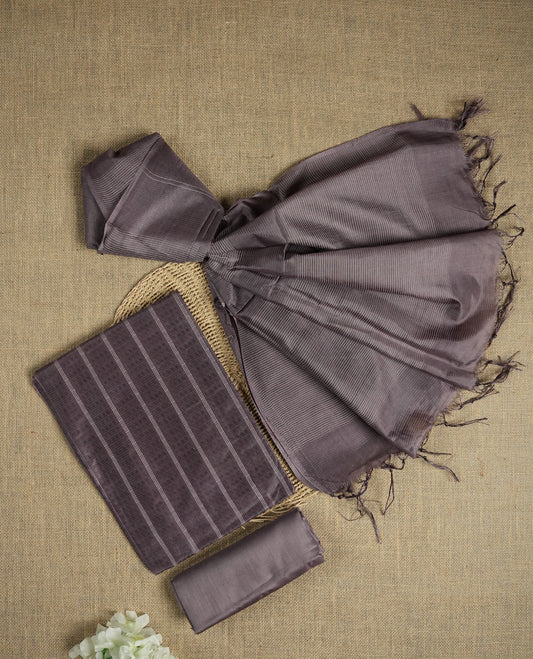 Dark pastel purple colour tussar suit material featuring a subtle self woven pattern and vertical lines on the body, paired with a lightweight matching dupatta with tassel edges and a plain bottom piece.